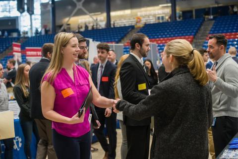 Students and alumni greeting potential employers at a career fair